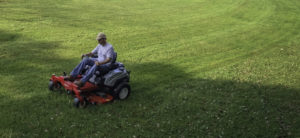 Man mowing a lawn with a red Exmark mower